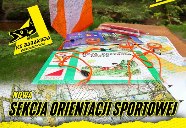 Na stole znajduje się mapa, książka o przygodach w lesie oraz kilka kolorowych元素, w tym pomarańczowe linki, na tle zielonego otoczenia leśnego, z widocznym logo klubu sportowego.