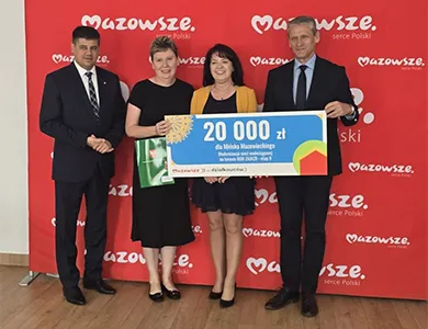 Cztery osoby stoją na tle czerwonej ściany z napisem "Mazowsze", trzymając dużą czekową kartę z kwotą 20 000 zł.