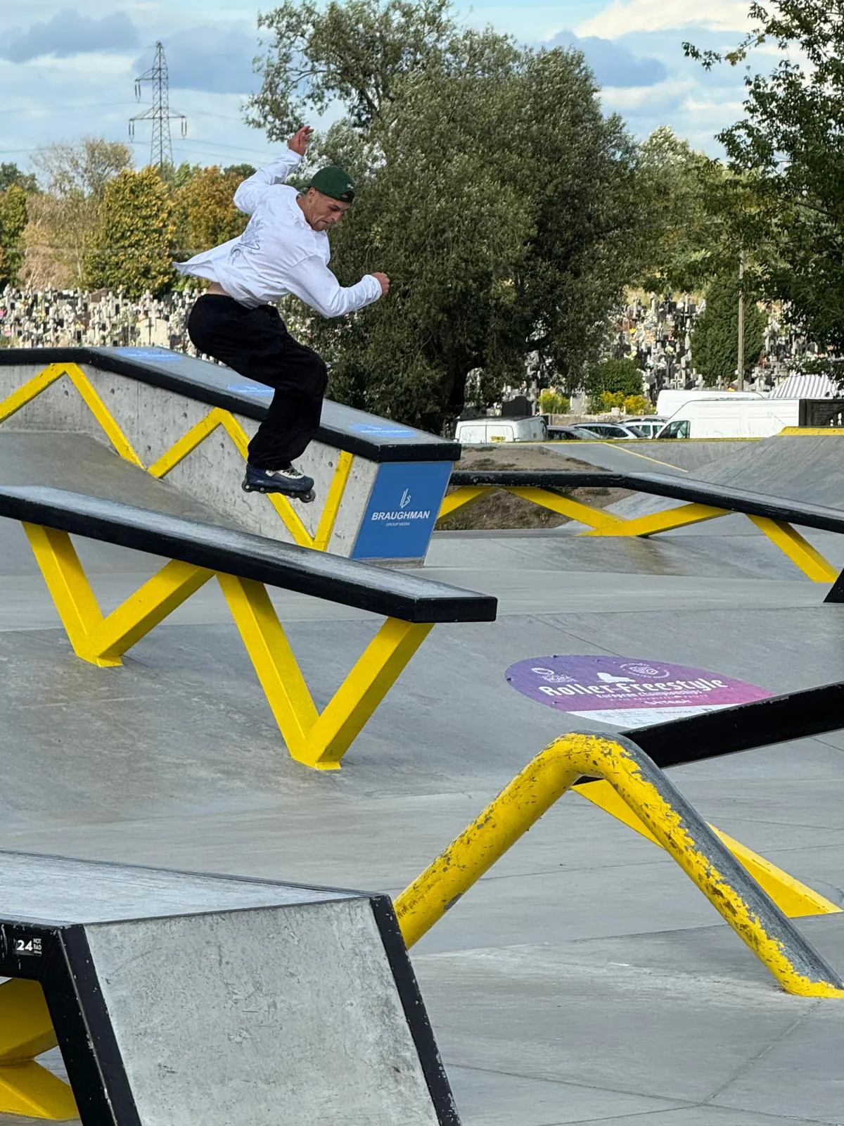 Mężczyzna na rolkach wykonuje trik na podwójnym poręczy w skateparku na zewnątrz w ciągu dnia.