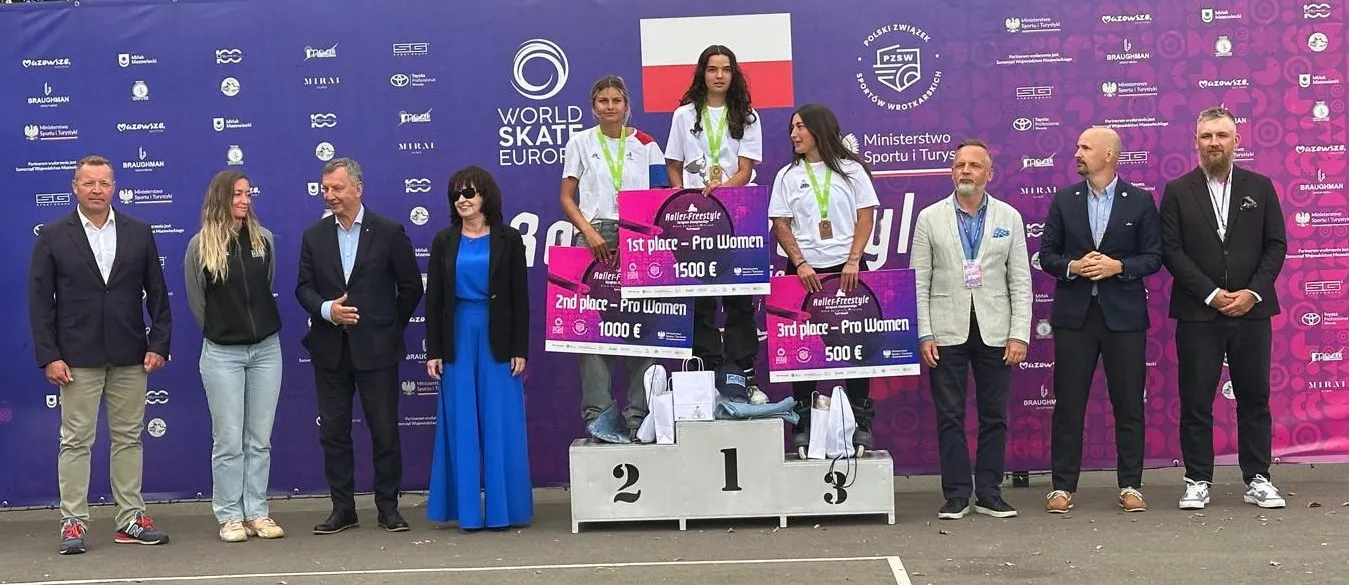 Trzy kobiety z medalami stoją na podium z nagrodami pieniężnymi za Roller Freestyle, wokół nich stoi osiem osób na tle fioletowej ścianki z logo World Skate Europe i polskiej flagi.